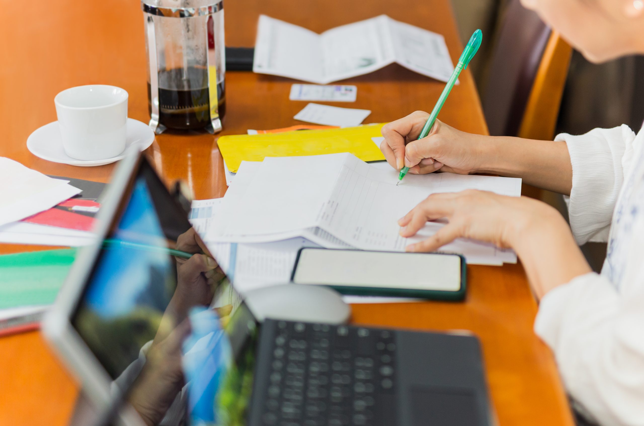 Woman paying bills online and writing notes at home.