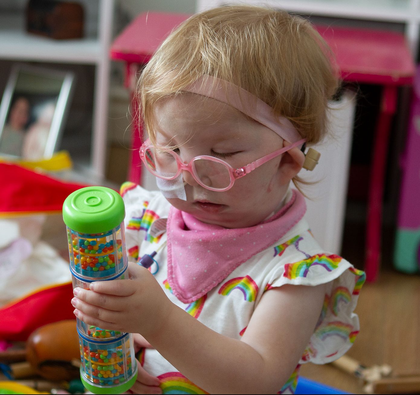 Photo of a child with pink glasses playing with a vibrant toy