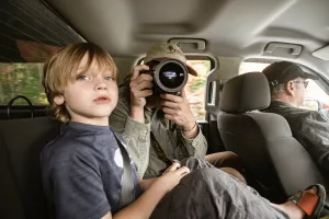 child and parent in car with camera