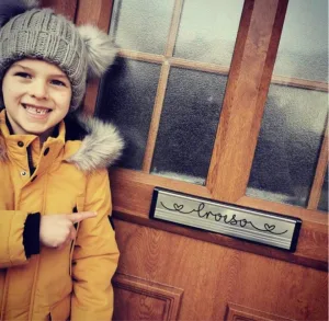 Ollie pointing at his handmade door sign.