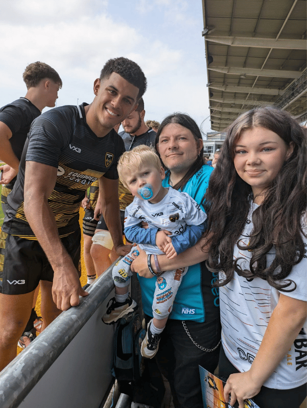 A photo of Rio, his Grandad Paul and auntie Kelcea at a rugby match, posing with Rio Dyer