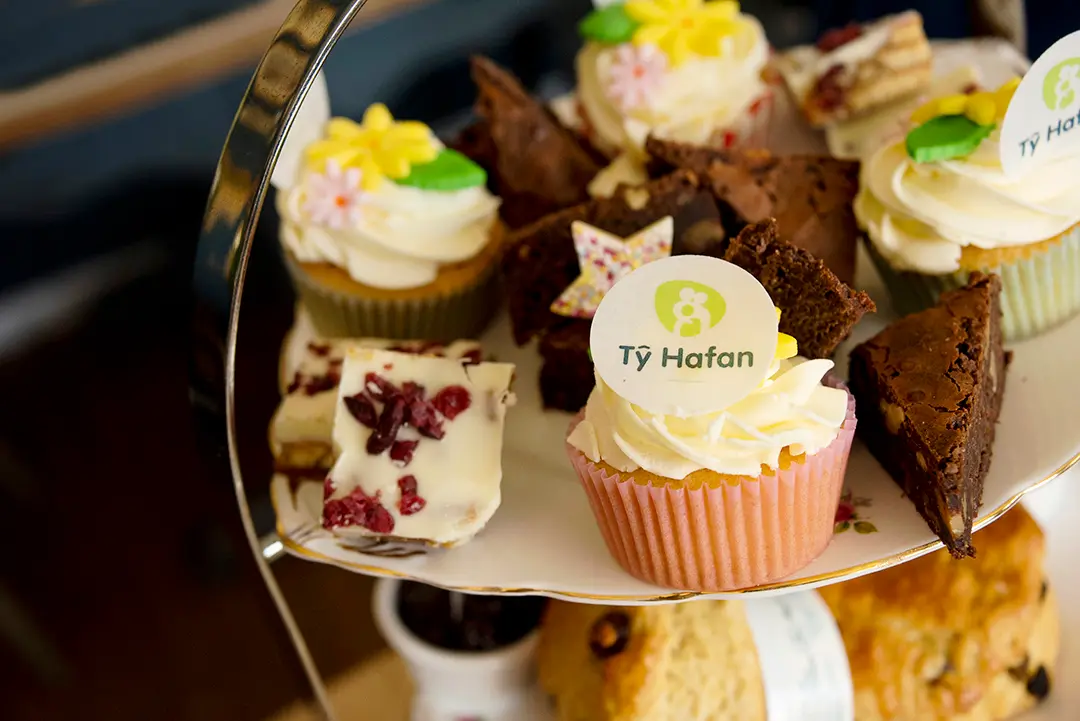 A photo of cupcakes and brownies. The central cupcake has the Ty Hafan logo