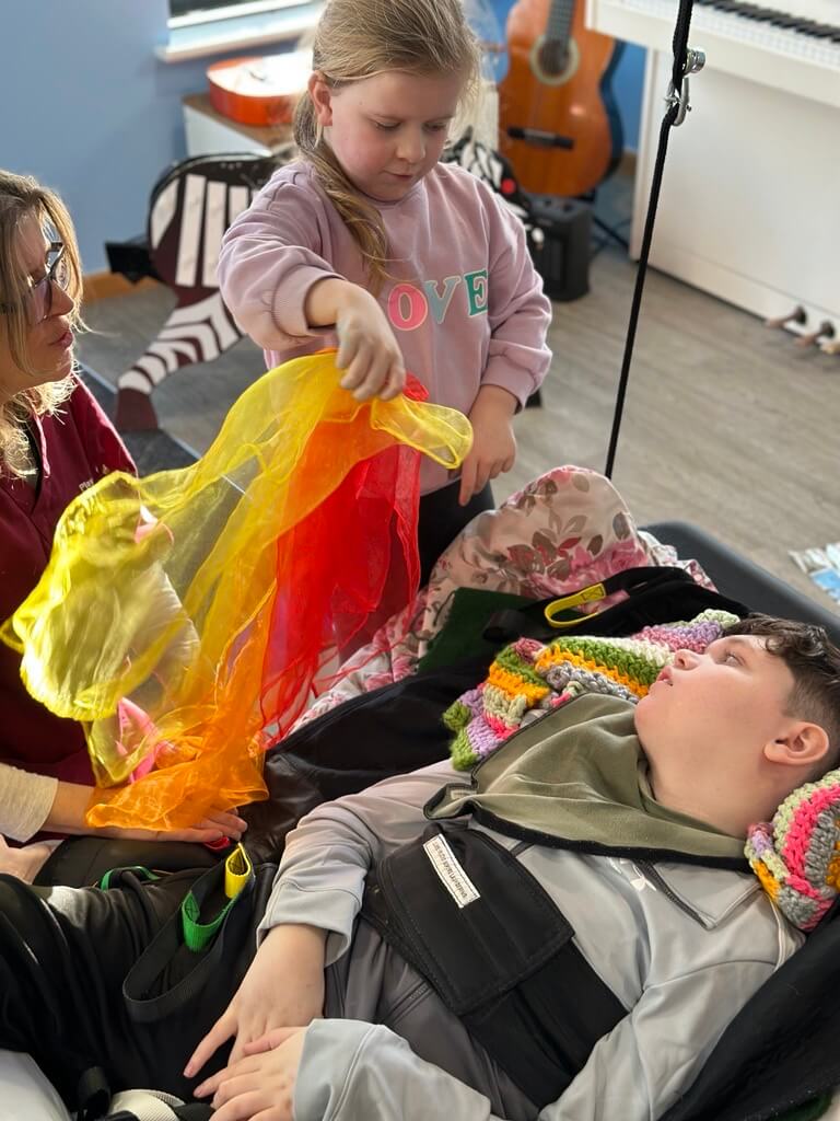 Sienna waves yellow, orange and red fabric for her brother Mason during a sensory story.
