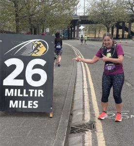 Cathy Gould points at a 26 miles sign in her running gear