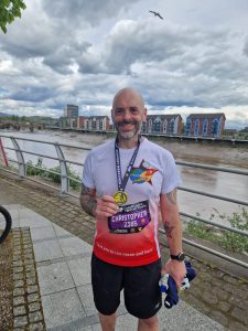 Chris Thomas in his running gear, wearing his Newport Marathon medal and smiling at the camera