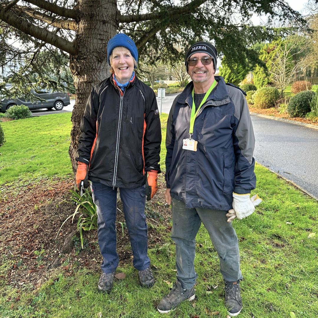 A photo of Brian and Karen standing in front of a tree in the ty hafan gardens in winter outfits
