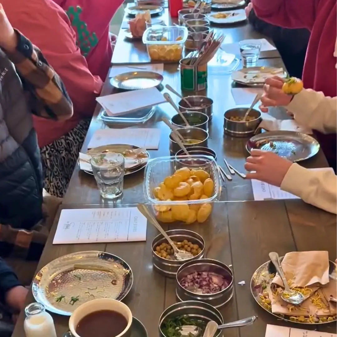 A photo of a long table at Mowglis Street Food with lots of small bowls of ingredients. You can see the hands of children making meals from the ingredients