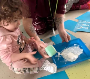 Ivy-Mai stamps a pain snowman with a member of the Play Team at Stay "N" Play