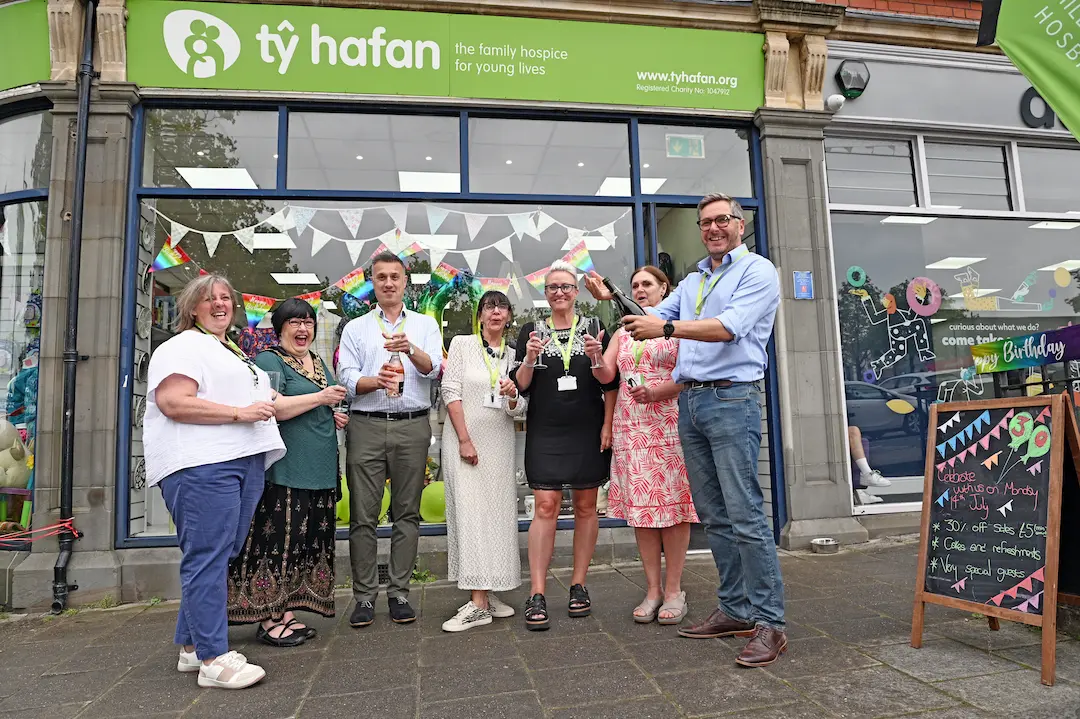 A group of staff make a toast outside the Caerphilly Tŷ Hafan shop